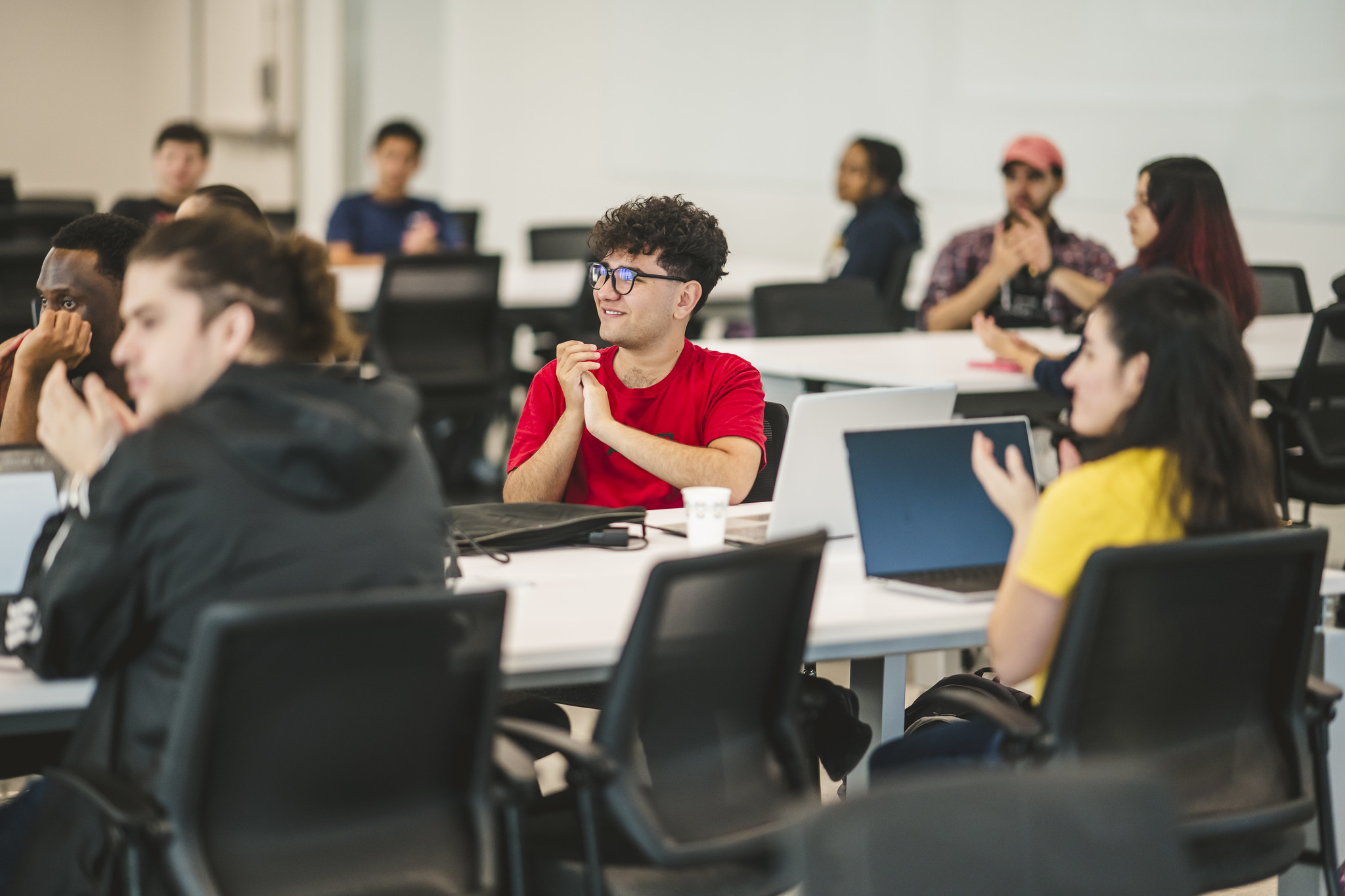 Students sitting at a round table clapping for speaker
