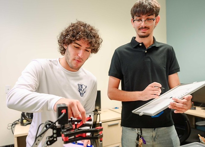 Two students working to alter a robot
