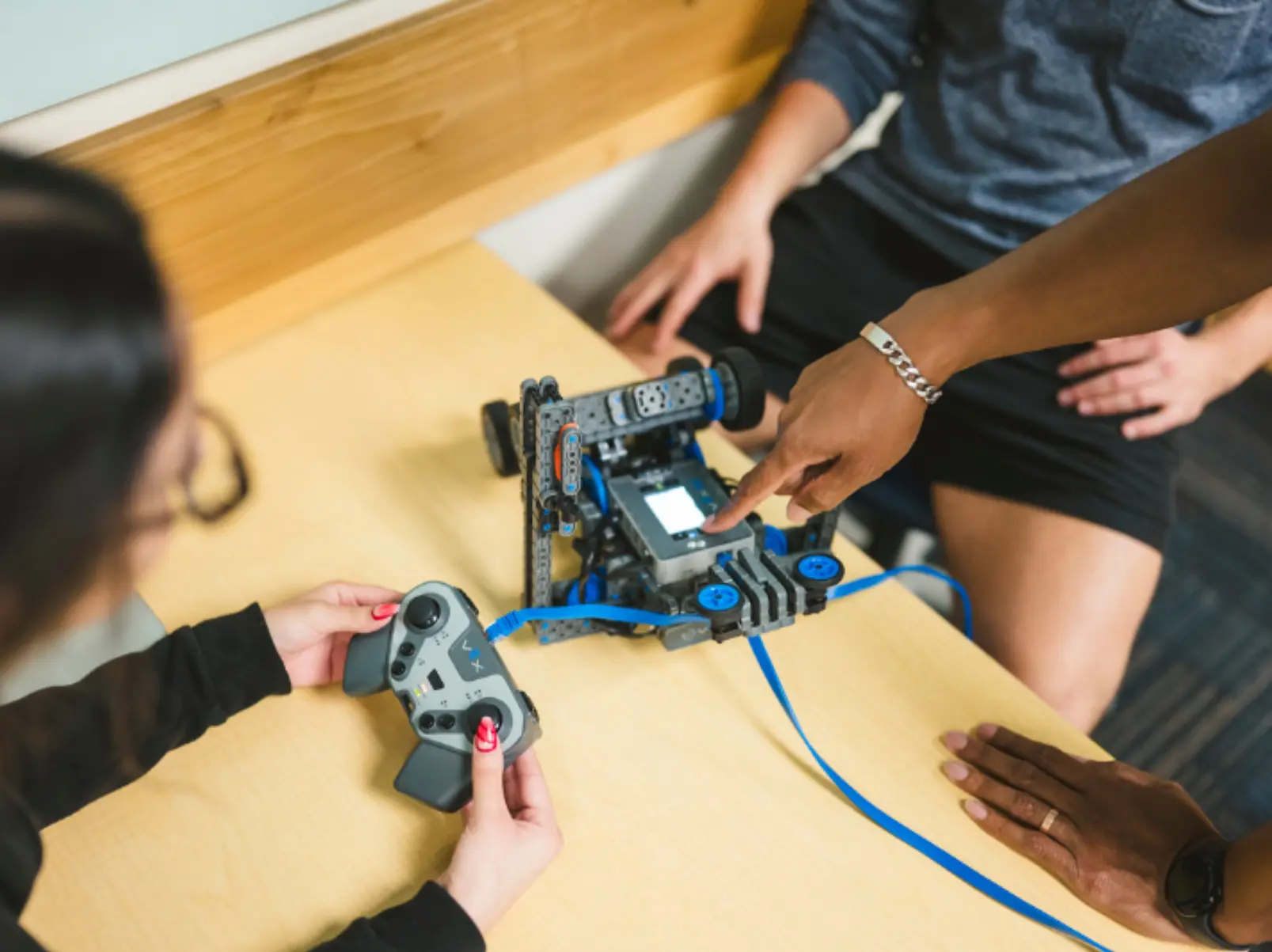 Individual pointing at robot piece and explaining to students