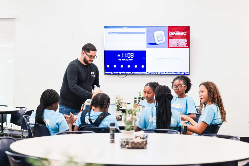 FIU Student assisting a group of students with a project