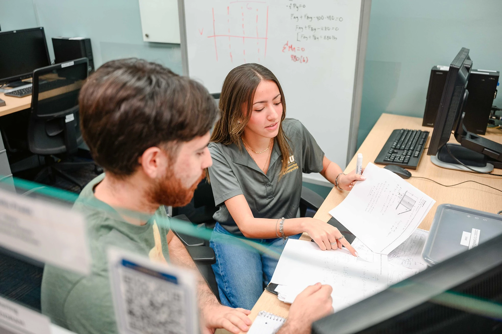 Student peer tutoring fellow student - pointing to problem on paper